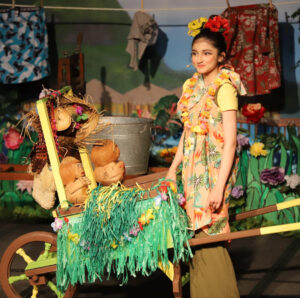 Girl performing on stage in costumes during a school theatre production.