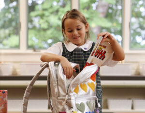 girl in school uniform with books and backpack
