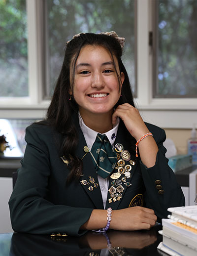 Student in uniform sitting at desk smiling
