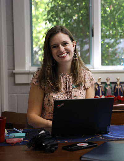 Teacher working in classroom on laptop smiling