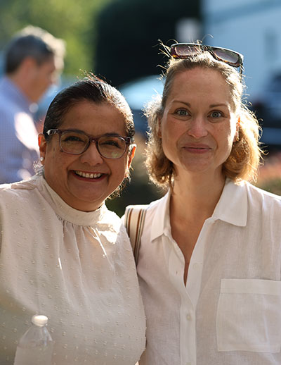 Two supportive moms smiling in white shirts