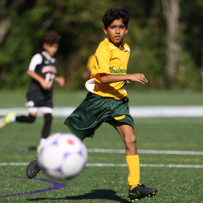 Boy playing soccer on turf field in jersey