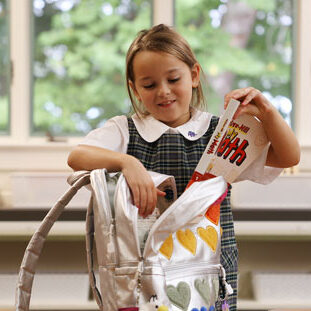 Admissions-Mega girl in school uniform with books and backpack