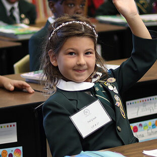 girl holding up hand in class